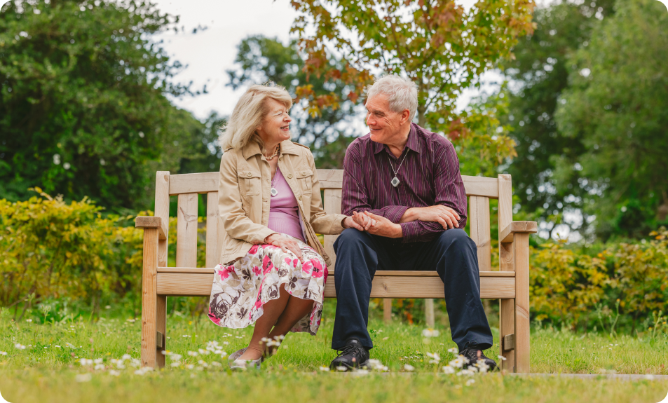 Two people sat on a bench holding hands.