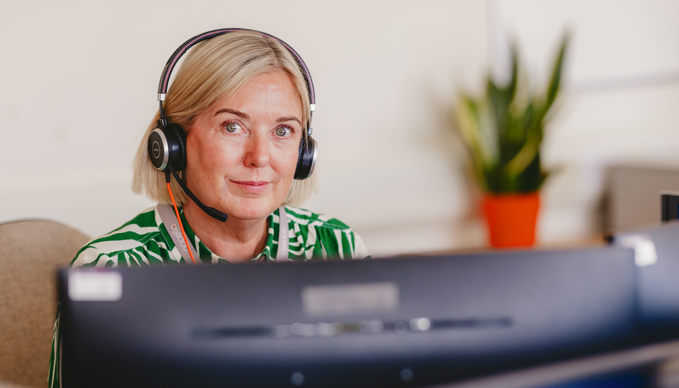 Female operator in green shirt looking at camera