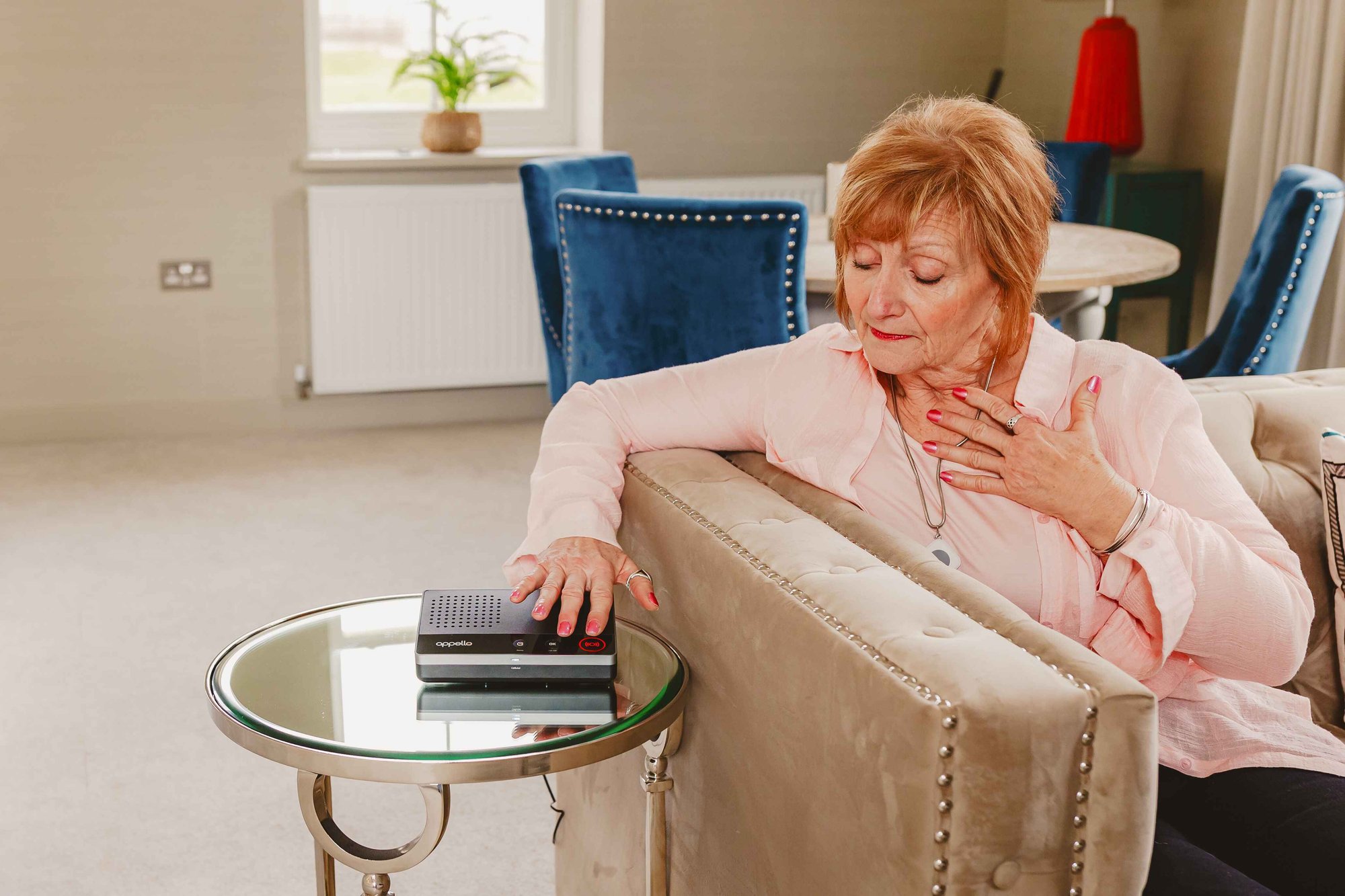 Elderly woman next to SmartLife unit on table.