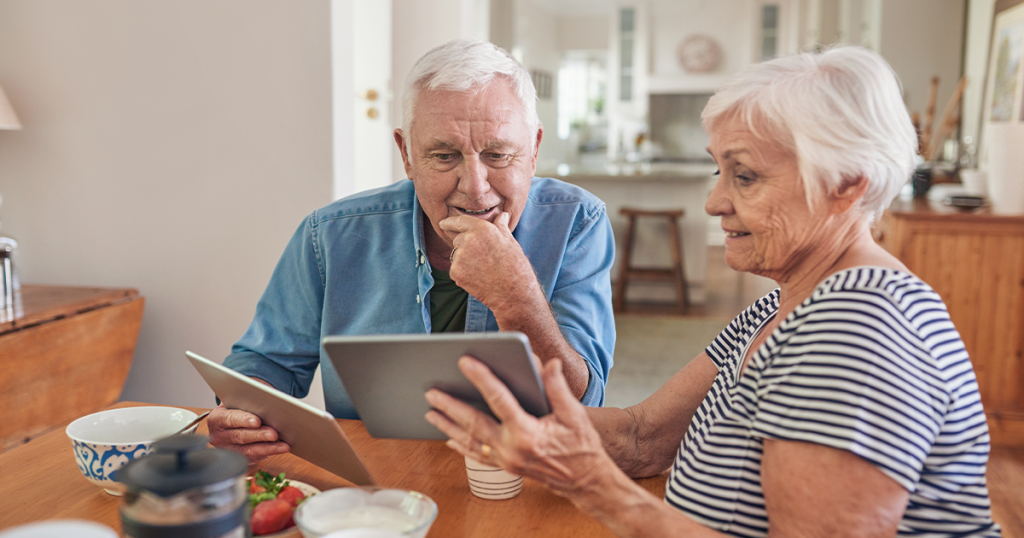 Two elderly people looking at ipads