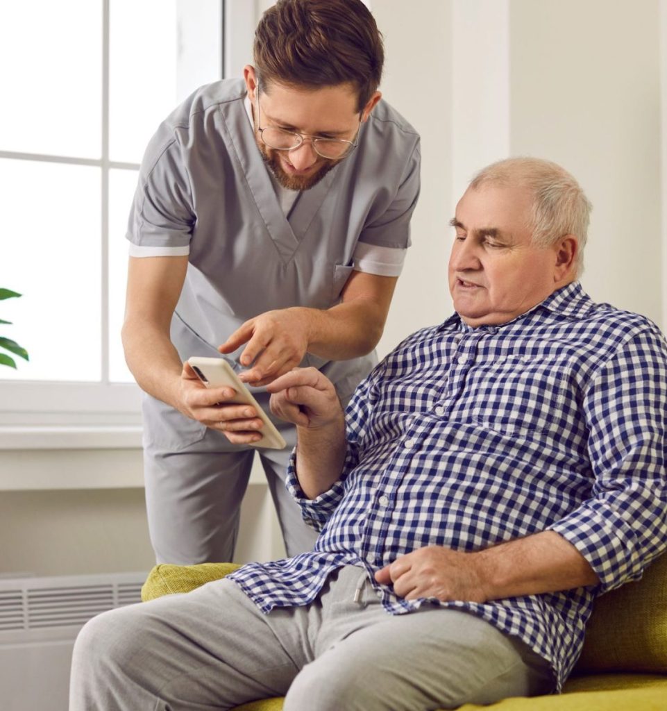 Young brunette nurse man helping a senior patient how to use smartphone.