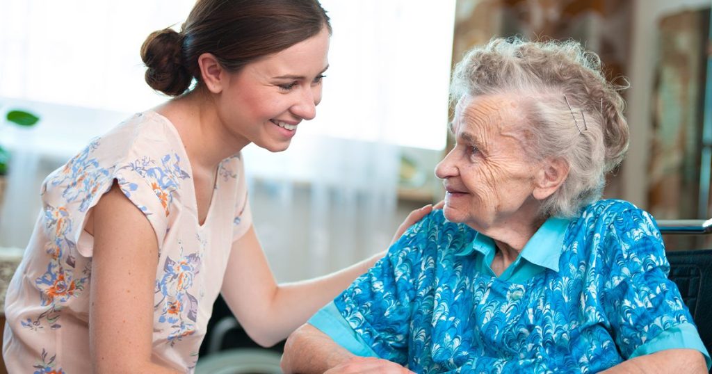 Elderly woman in care home with carer.